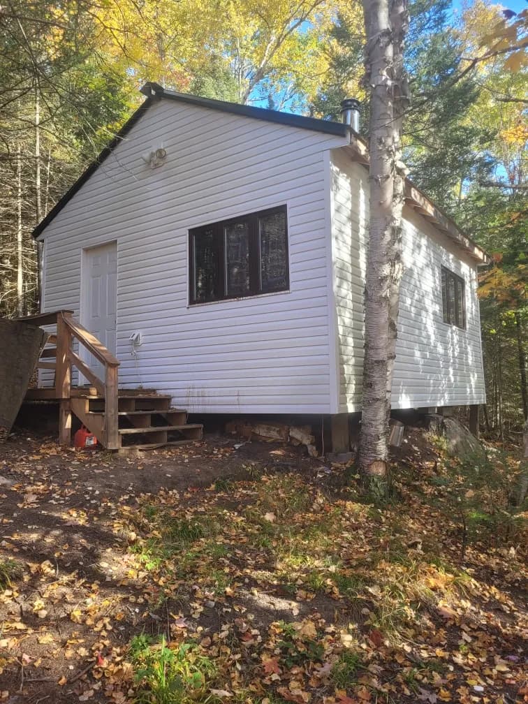 Cash home purchase, Sylvan Lake, Alberta White-sided seasonal cottage tucked into mature trees near Sylvan Lake, Alberta — the kind of original Cottage Area or summer-village property Canadian Home Buyers purchases for cash, as-is.